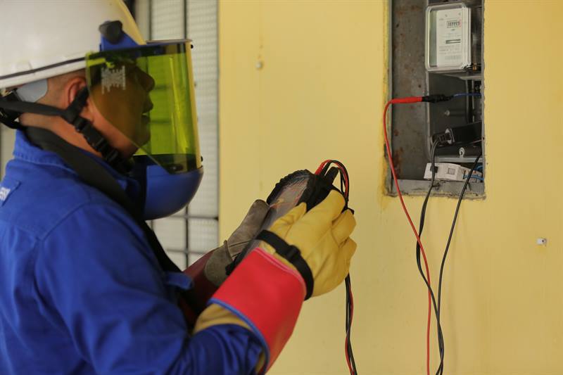 Hombre con casco y careta haciendo una labor en un medidor de energía