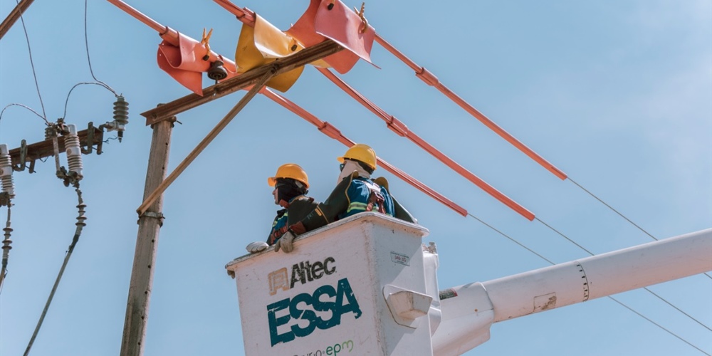 trabajadores sobre un carro canasta realizan labores de mantenimiento a las redes de energía