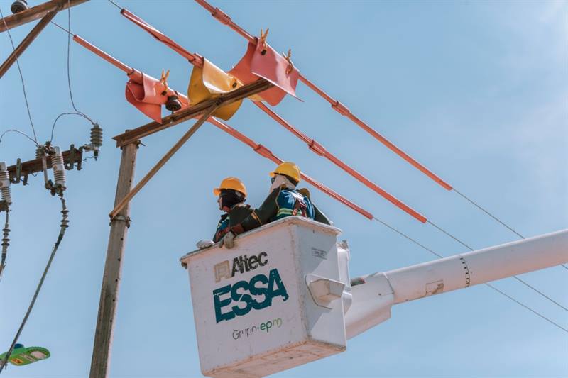 trabajadores sobre un carro canasta realizan labores de mantenimiento a las redes de energía