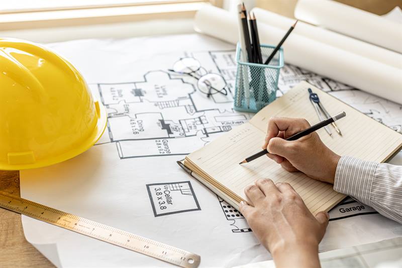 Fotografía hombre diseñando plano técnico: Normas técnicas en transición